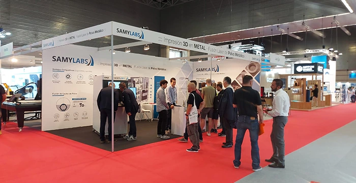 Stand de SamyLabs en ADDIT3D 2022, con visitantes alrededor de la máquina ALBA 300