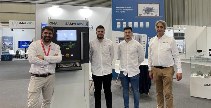Cuatro personas del equipo de SamyLabs en el stand de ADDIT3D 2023, con la máquina detrás