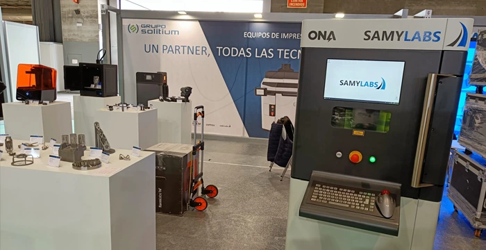 Stand en MetalMadrid 2022 con la ALBA 300 y un expositor de piezas metálicas impresas