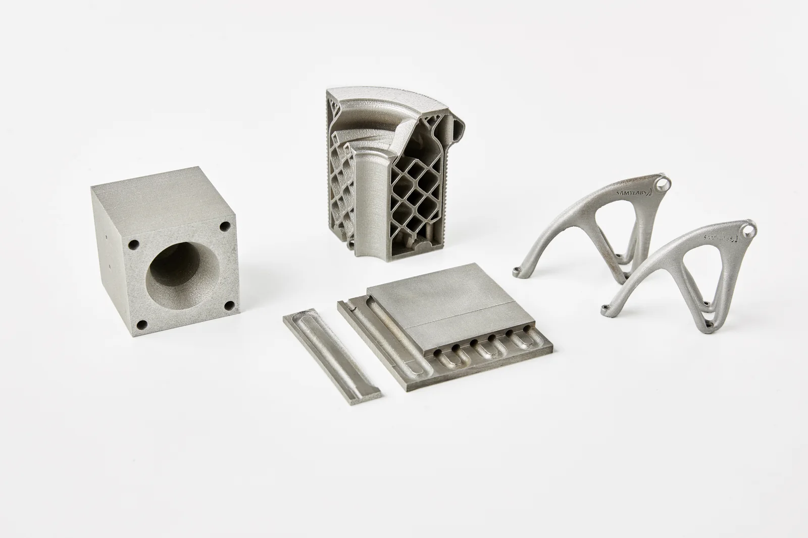 Conjunto de piezas fabricadas por impresión 3D en metal: colector, estructura reticular, horquilla optimizada topológicamente y placas