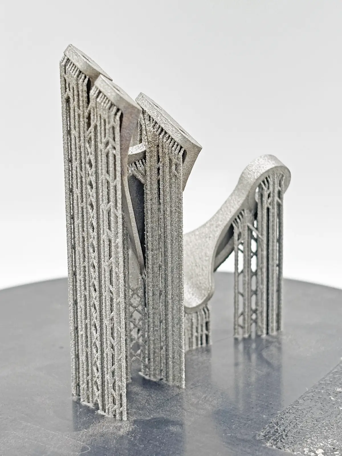 Pieza estructural impresa en metal sobre la plataforma, todavía con sus soportes de celosía