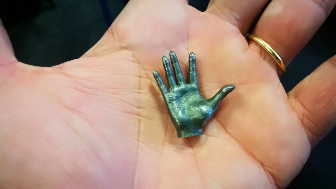 Pieza en miniatura impresa en metal sostenida en la palma de la mano