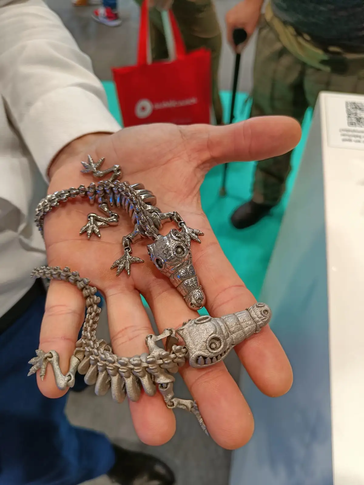 Muestrario de piezas pequeñas impresas en 3D en metal sostenidas en la mano