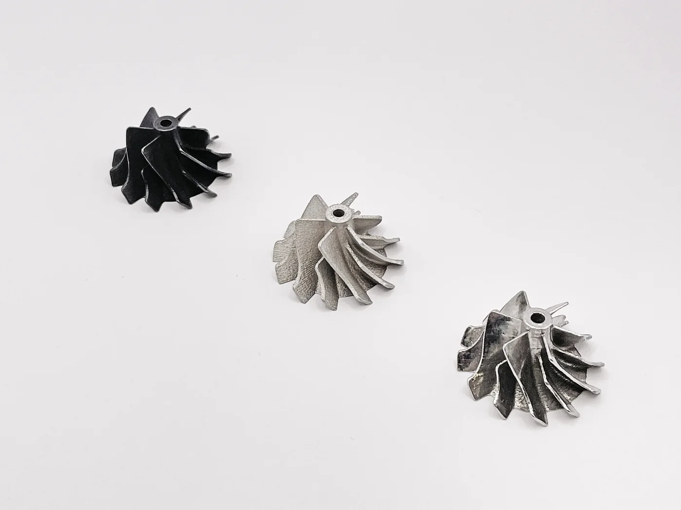 Tres rodetes de turbina de distintos tamaños fabricados por impresión 3D en metal